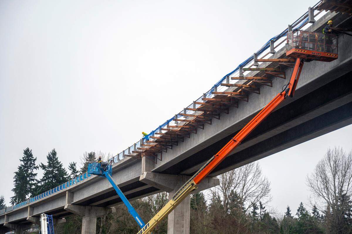 Construction workers install emergency guardrails high above Pacific Highway South at South 208th Street. It’s the only point where the line crosses state Route 99.