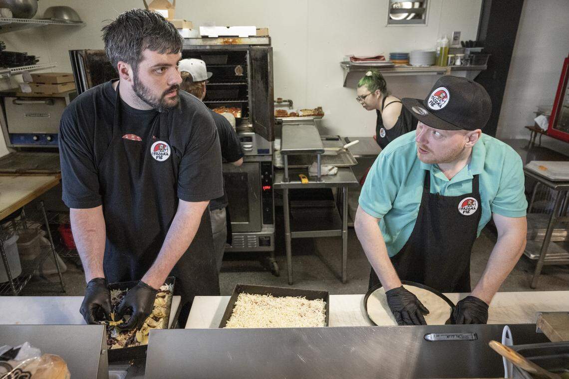 Pizza cook Nick Westover, left, and manager Lucas Drawdy, right, prepare pizzas behind the counter at Tacoma Pie on April 10. Fridays are busy, with six or so staffers moving through the open kitchen and breezy dining room to patio.