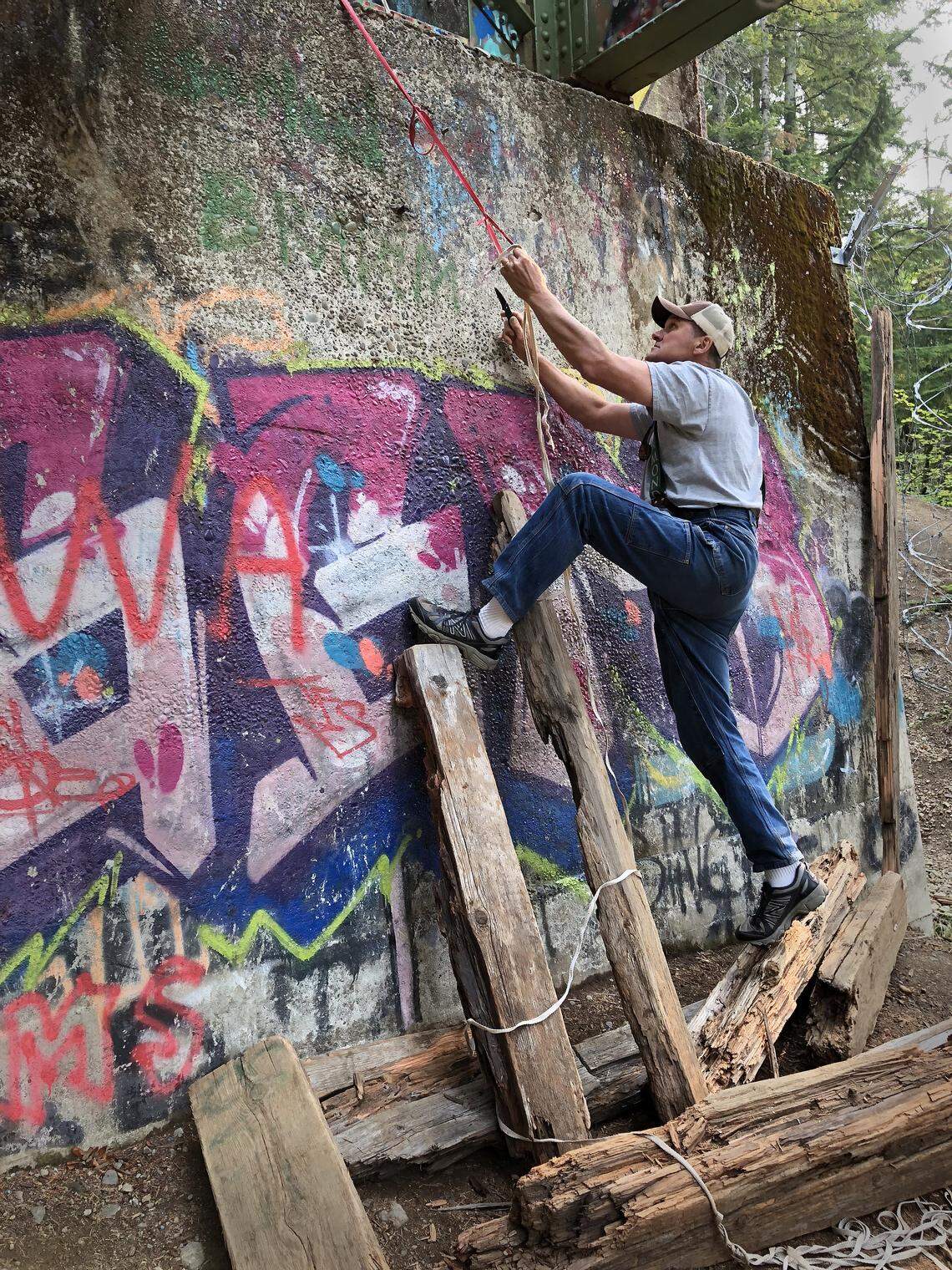 Matt Nixon of Green Diamond Resource Company cuts a rope used by people to climb up a support for the Vance Creek Bridge. It’s a constant battle to keep people from climbing onto the dangerous bridge, he said.