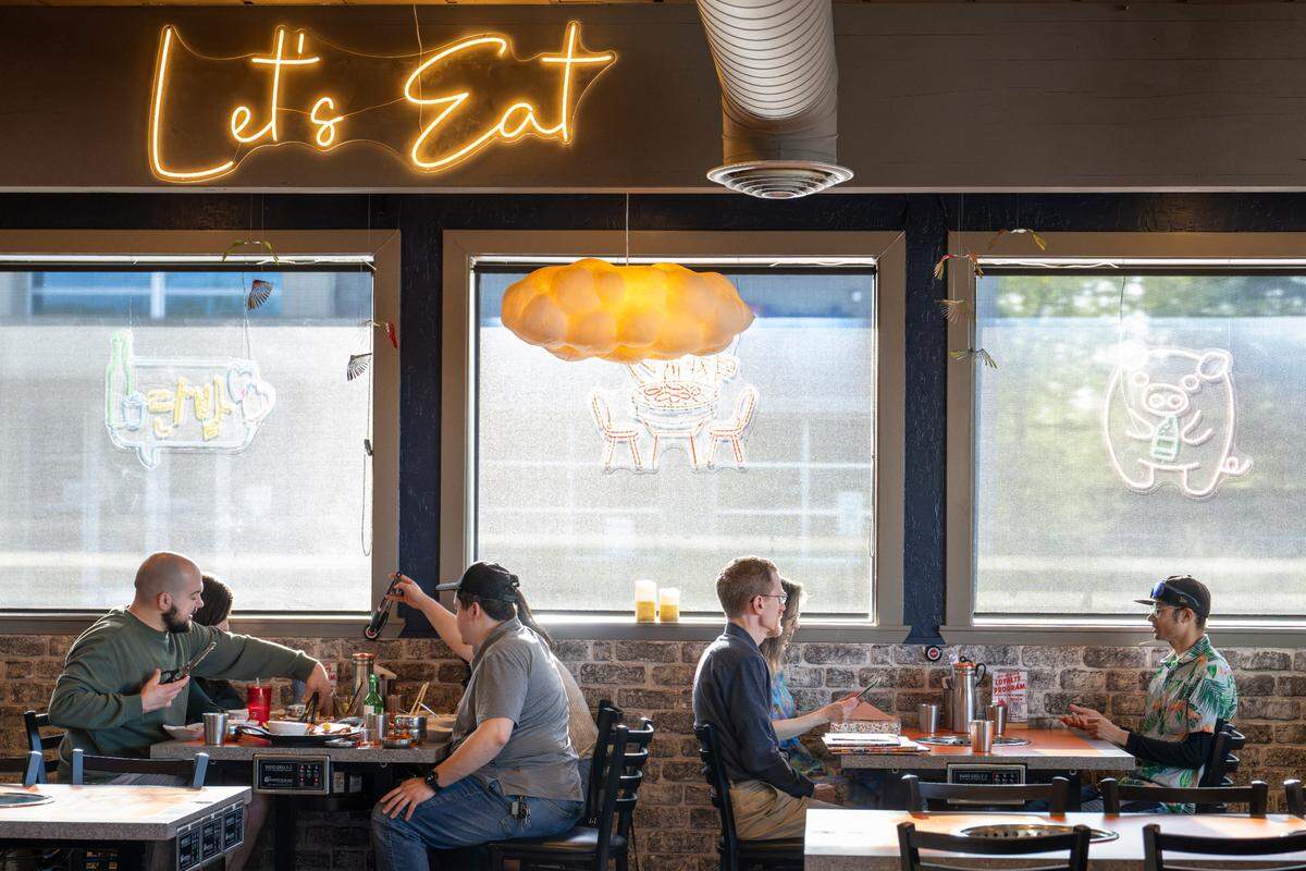 Diners sit around built-in grills at tables at Mukja Korean BBQ on Friday, April 18, 2025, in Puyallup, Wash.
