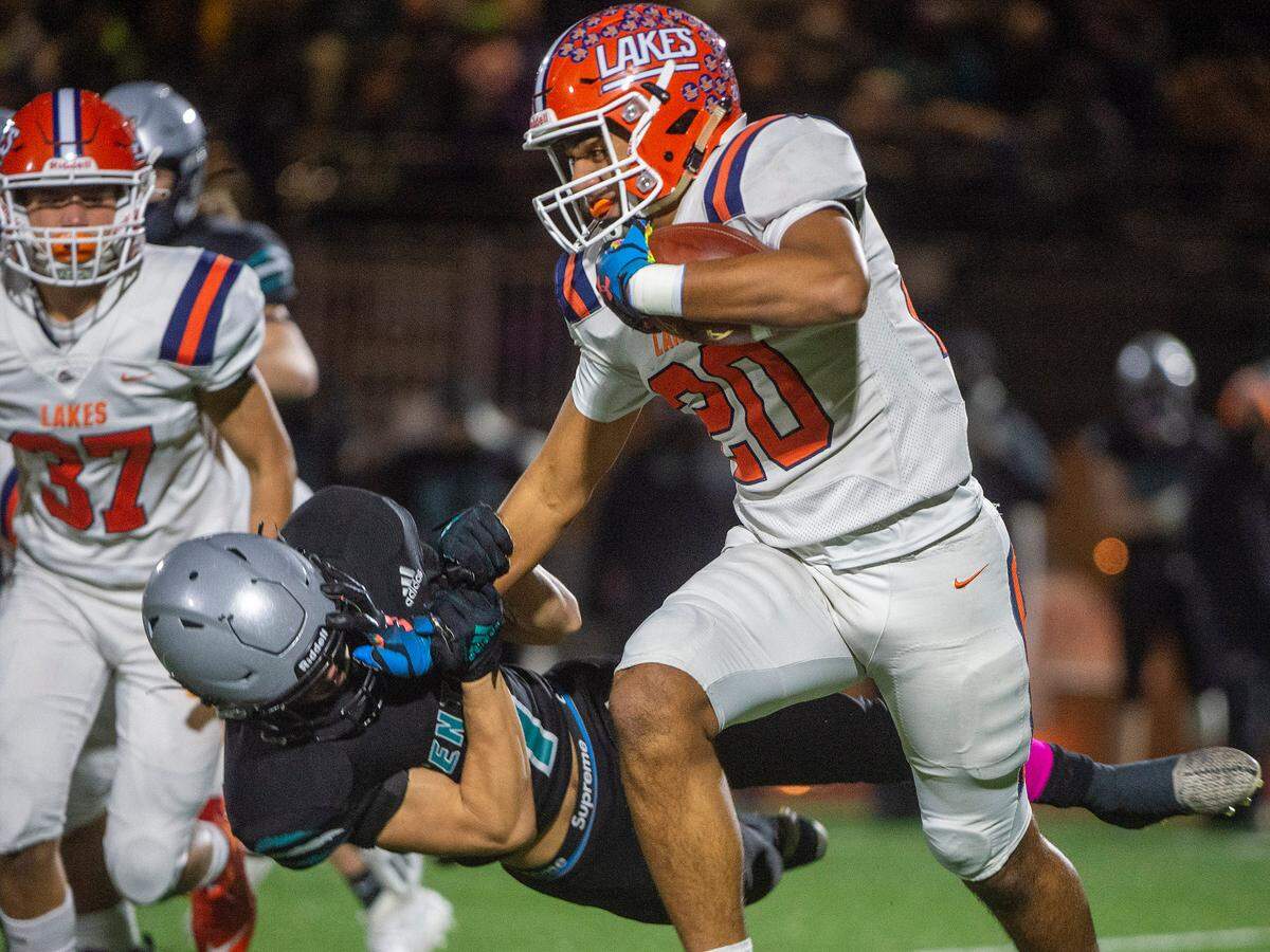 Lakes running back Leo Pulalasi stiff arms Spanaway Lake’s Blake Ongais as he runs upfield during the first quarter of a 3A Pierce County League game on Friday at Art Crate Field in Spanaway.