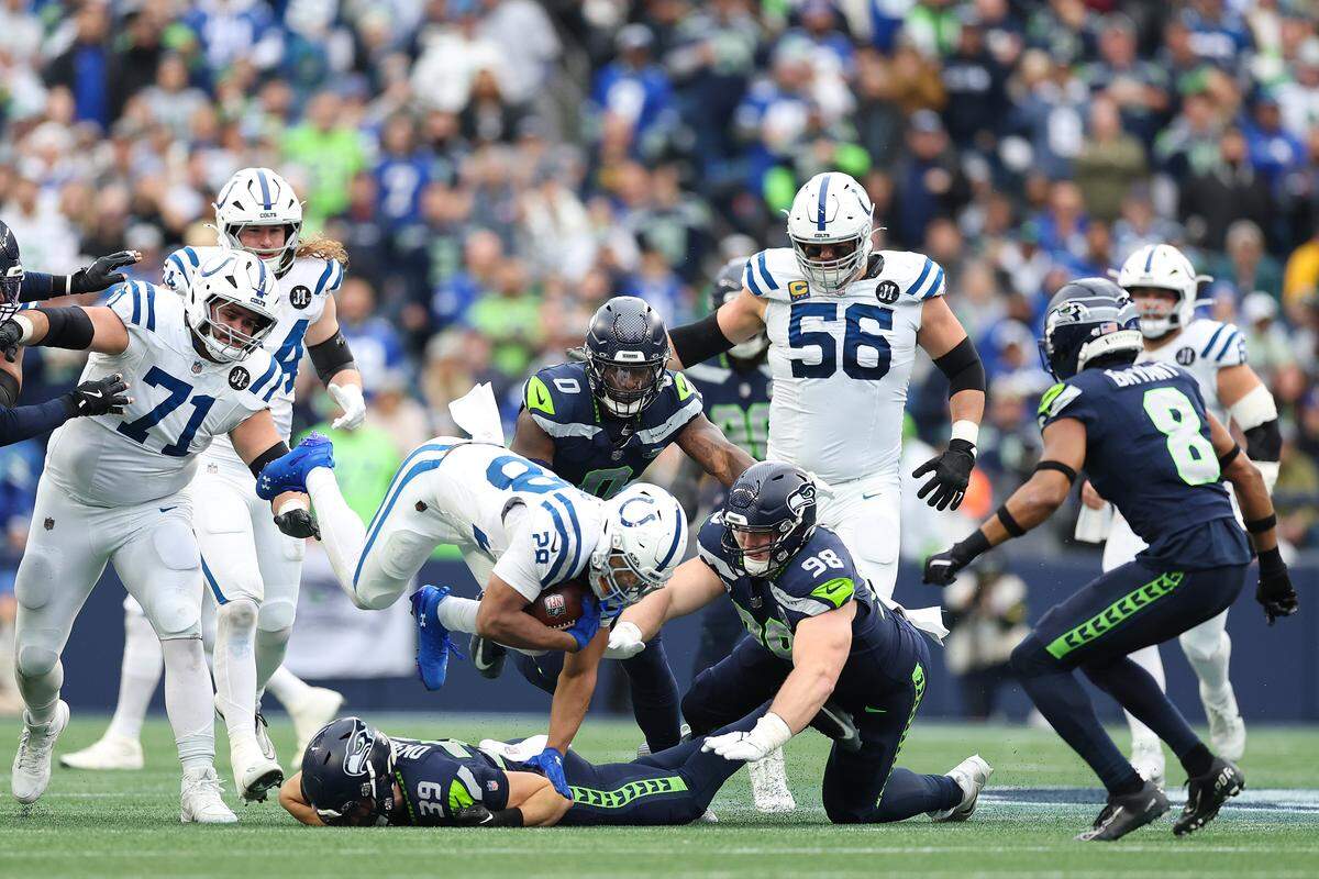 SEATTLE, WASHINGTON - DECEMBER 14: Jonathan Taylor #28 of the Indianapolis Colts carries the ball against Ty Okada #39 and Rylie Mills #98 of the Seattle Seahawks during the second quarter at Lumen Field on December 14, 2025 in Seattle, Washington. (Photo by Steph Chambers/Getty Images)