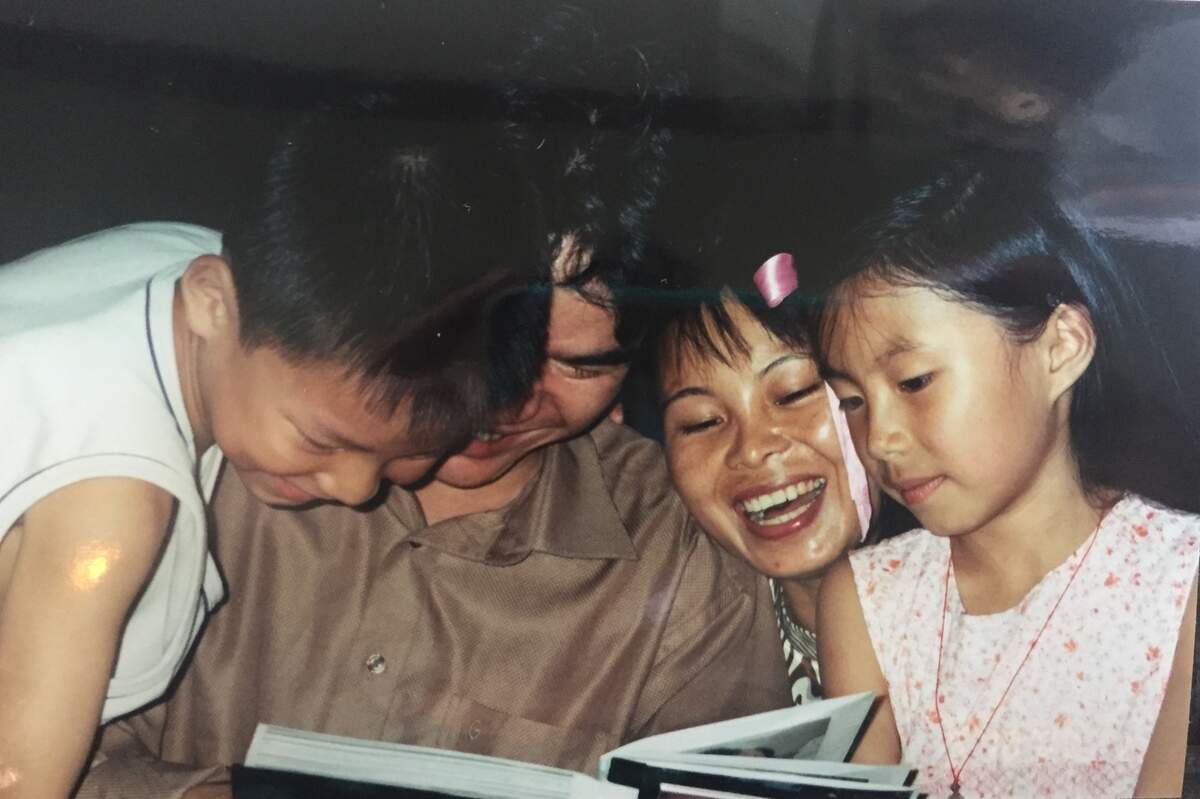 Jesse Newman’s and Molly Renfrow’s birth parents and brother look at a photo album showing the twins’ life in America in 2003.