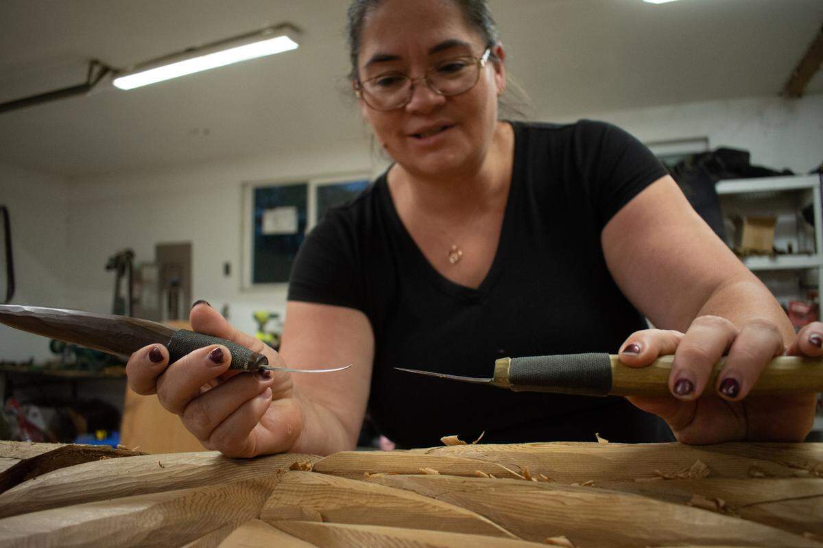Andrea Wilbur-Sigo, a member of the Squaxin Island Tribe, shows the differences between her handmade knives at her home workshop in Shelton, Wash., Thursday, Nov. 4. The carver is known for large pieces of public art including welcome figures, house posts and spindle whorls as well as beading and weaving.