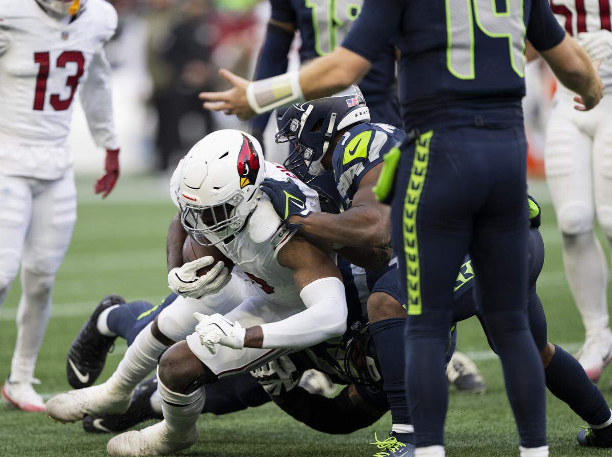 Arizona Cardinals linebacker Josh Sweat (10) is tackled after recovering a Seattle Seahawks quarterback Sam Darnold (14) turnout off a tip during the third quarter of the game at Lumen Field, on Sunday, Nov. 9, 2025, in Seattle.