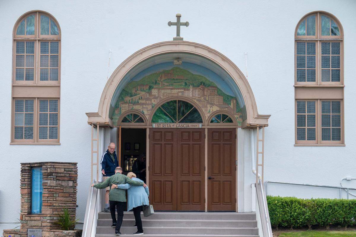Parishioners at St. Rita of Cascia walk up the steps toward the church entrance for the final Mass before the church will be merged with several other small parishes in the area on Wednesday, June 8, 2022, in Tacoma.