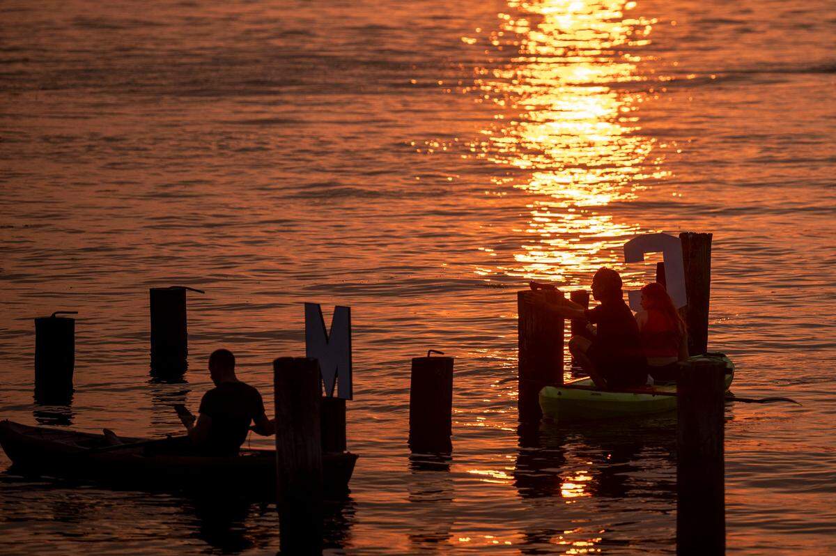 John James Nelson (center) works with his daughter, Kyleena Shipman (right), attaching letters to off-shore pilings at Titlow Beach at sunset on Friday, Aug. 9, 2024, in Tacoma, Wash.