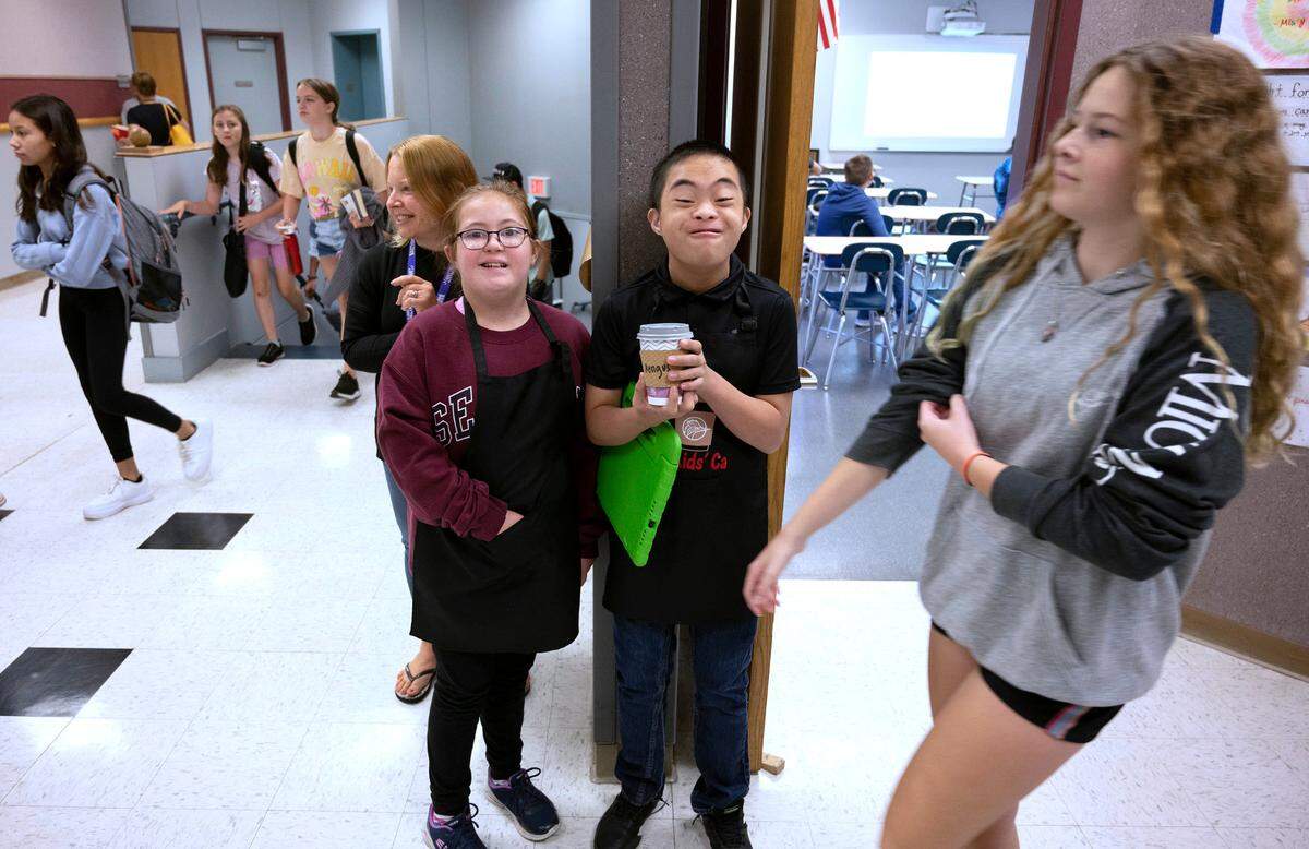 Kate Buerer and Hans Cagabcab wait for the hallway to clear as they deliver a hot chocolate from the Cool Kids Cafe at Goodman Middle School in Gig Harbor, Washington, on Thursday, Sept. 15, 2022.