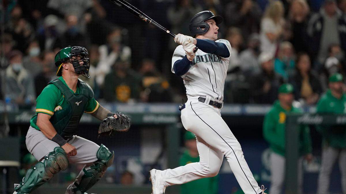 Seattle Mariners’ Jarred Kelenic follows through on a two-RBI double as Oakland Athletics catcher Yan Gomes, left, looks on, during the sixth inning of a baseball game, Wednesday, Sept. 29, 2021, in Seattle. Mitch Haniger and Ty France scored on the play. (AP Photo/Ted S. Warren)