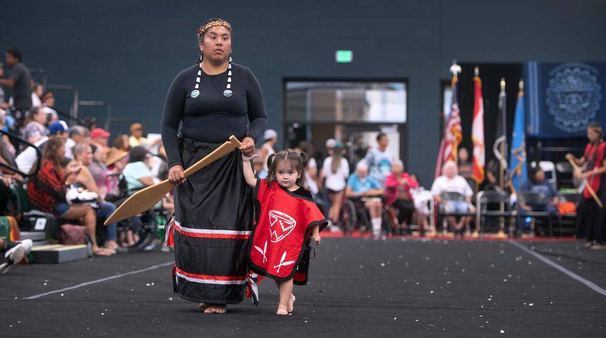 Two-year-old Syvina “Sugar” White Eagle accompanies her aunt, Deidra Hawkes of Chehalis as they perform with the Chehalis canoe family during the Canoe Journey 2023 Protocol at the Muckleshoot Pow Wow Grounds events center in Auburn, Washington, on Thursday, Aug. 3, 2023.