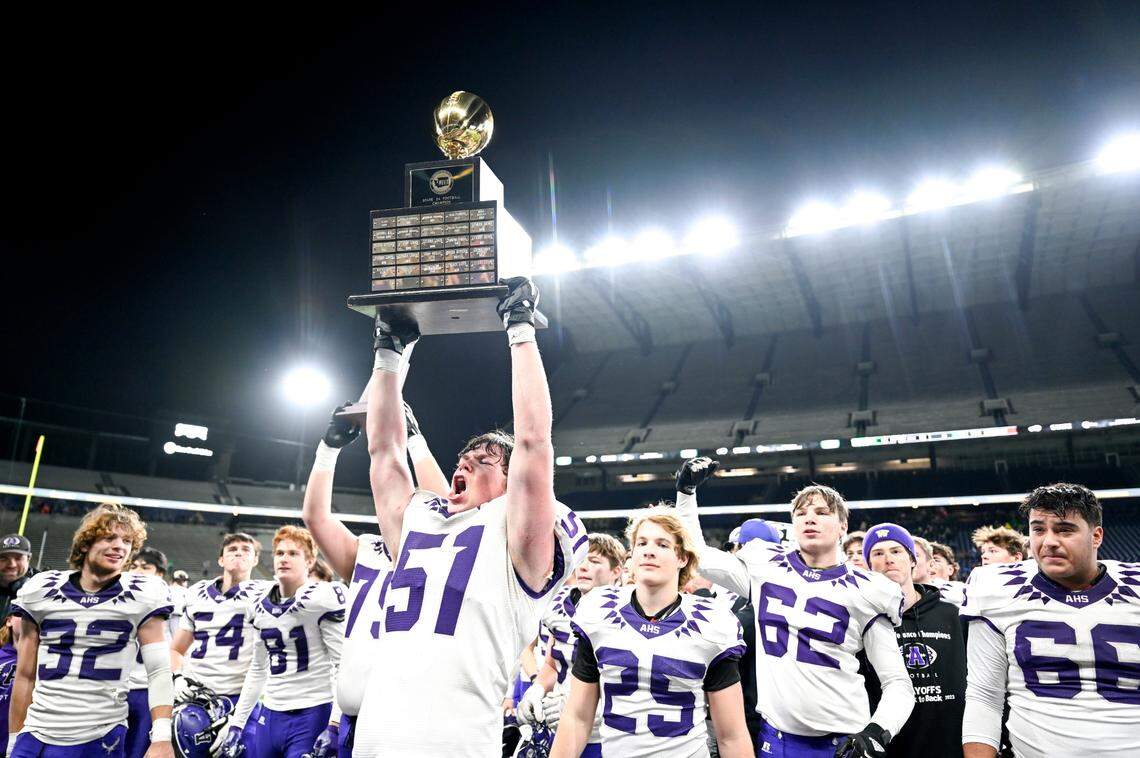 Anacortes’s Evan Hopps (60) holds the 2A state championship trophy after their 60-30 victory against Tumwater in the 2A state championship game at Husky Field, Saturday, Dec. 2, 2023, in Seattle, Wash.