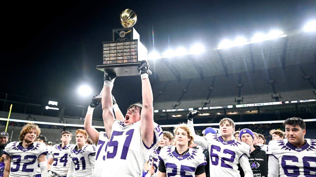 Anacortes’s Evan Hopps (60) holds the 2A state championship trophy after their 60-30 victory against Tumwater in the 2A state championship game at Husky Field, Saturday, Dec. 2, 2023, in Seattle, Wash.