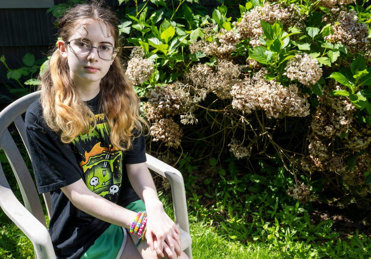 Phoebe sits in their backyard for a portrait on Thursday, May 1, 2025, in Tacoma.