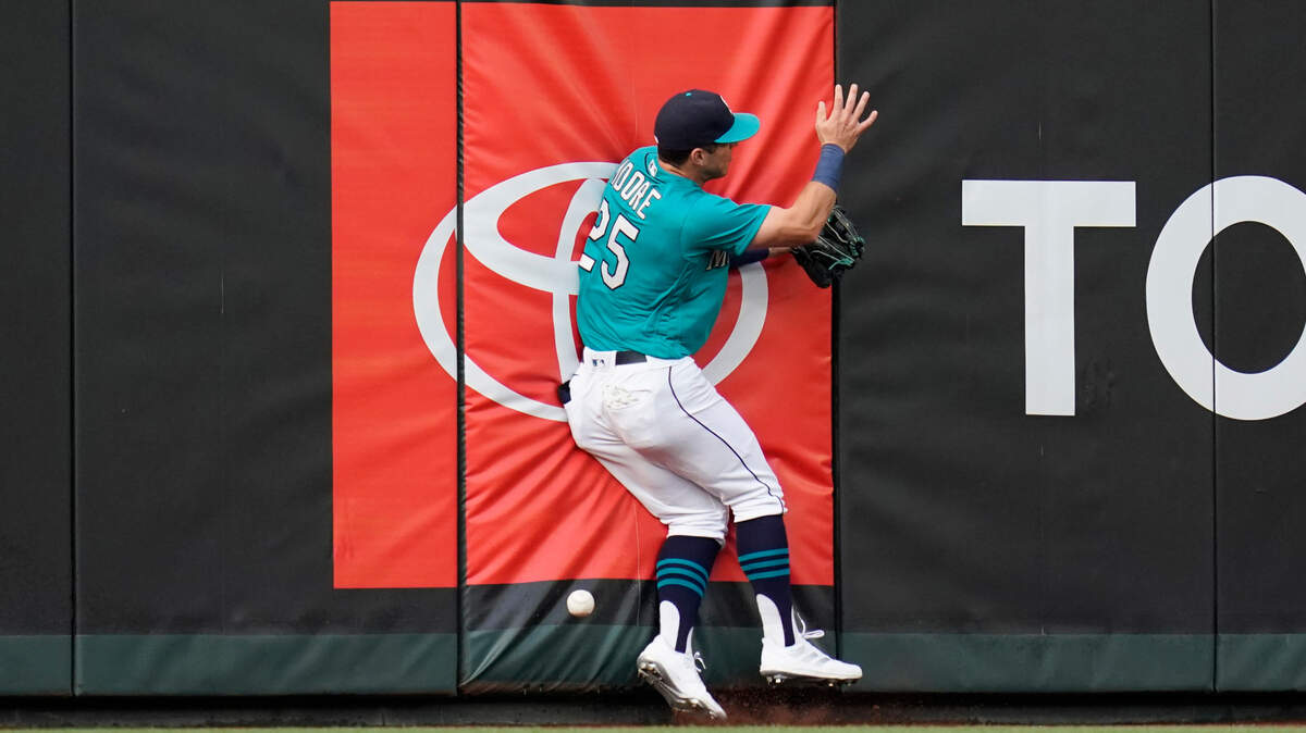Seattle Mariners left fielder Dylan Moore collides with the wall after chasing a deep fly that dropped in for a single by Kansas City Royals’ Salvador Perez during the first inning of a baseball game Friday, Aug. 27, 2021, in Seattle. (AP Photo/Elaine Thompson)