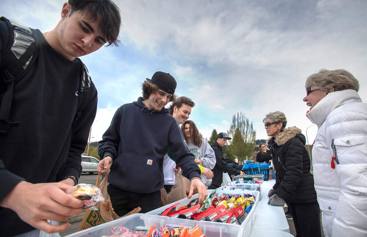 Sumner High students (from left) Dylan Kyser, Zach Peterson, Caden Davis and Jake Majors pick out snacks from the Mother 2 Many church outreach giveaway at the Sumner Skate Park in Sumner, Washington, on Wednesday, April 13, 2022.