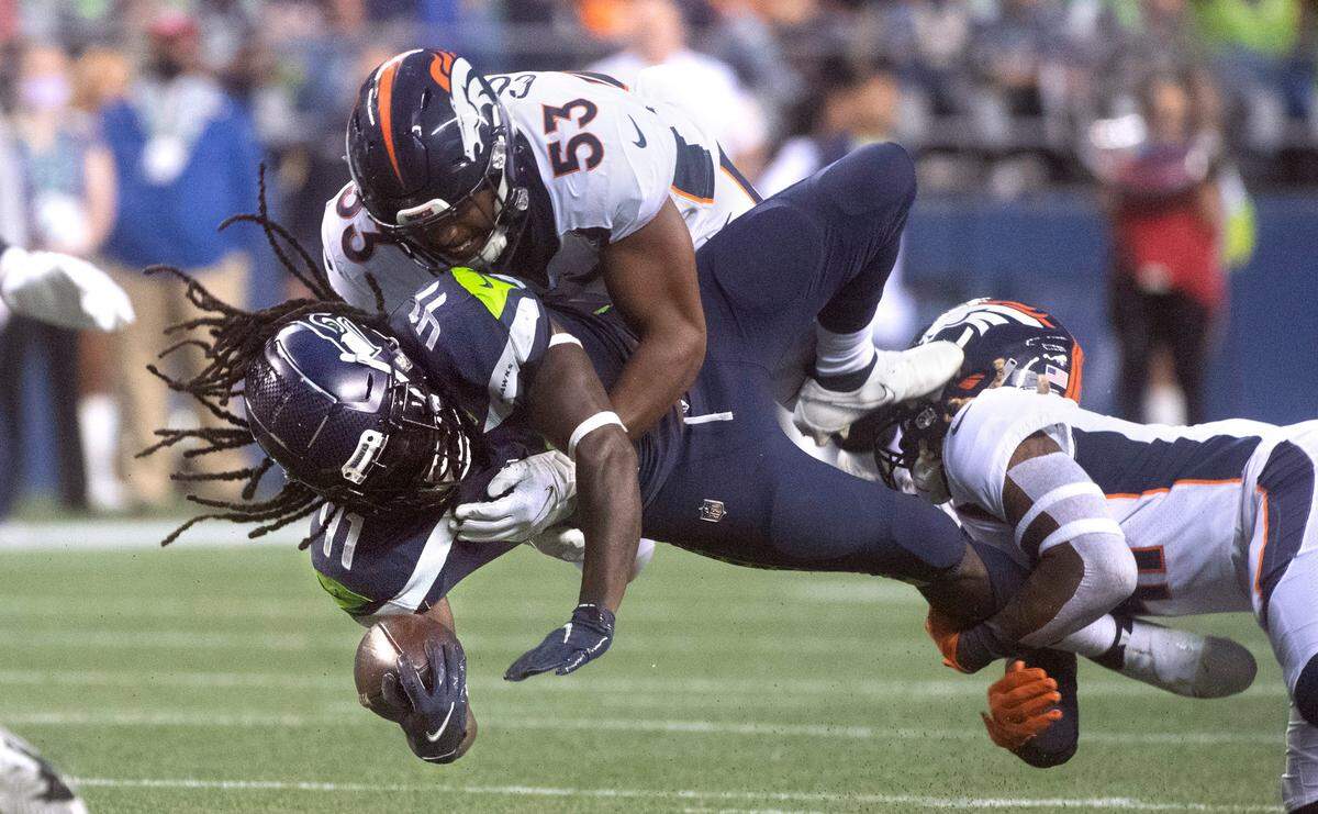 Seahawks running back Alex Collins is brought down by Broncos defenders Jonathon Cooper (53) and Jamar Johnson during Saturday night’s NFL preseason football game at Lumen Field in Seattle, Washington, on Saturday, Aug. 21, 2021.