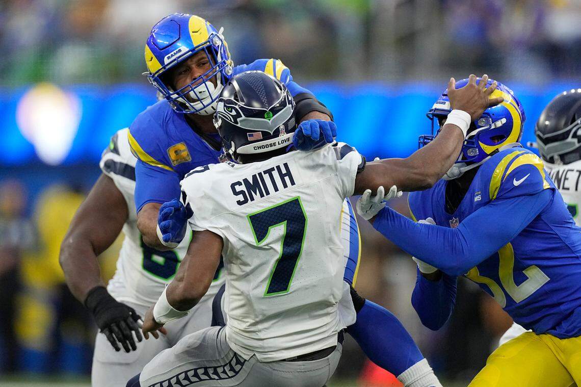 Seattle Seahawks quarterback Geno Smith (7) is injured while being tackled by Los Angeles Rams defensive tackle Aaron Donald, left, and linebacker Ochaun Mathis, right, during the second half of an NFL football game Sunday, Nov. 19, 2023, in Inglewood, Calif. (AP Photo/Mark J. Terrill)
