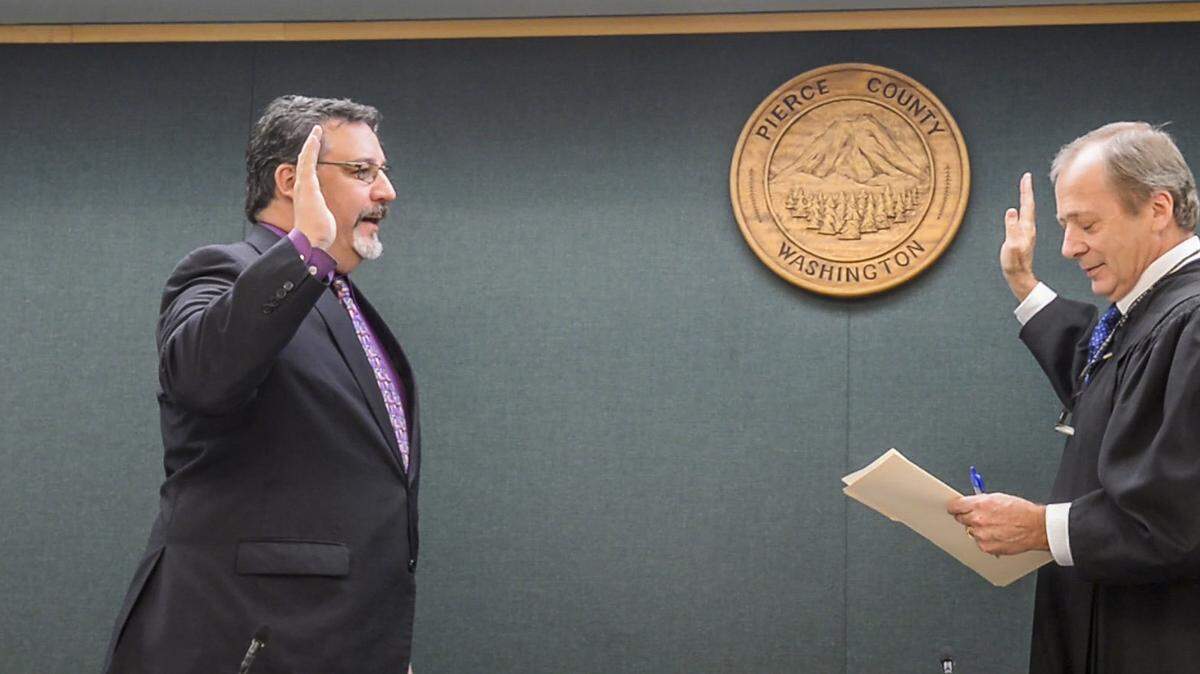 Marty Campbell recites his oath of office as led by Judge Garold Johnson (right) in the Pierce County Council chambers January 2, 2019, shortly after he was elected. Campbell was elected as the Pierce County Assessor-Treasurer in 2024.