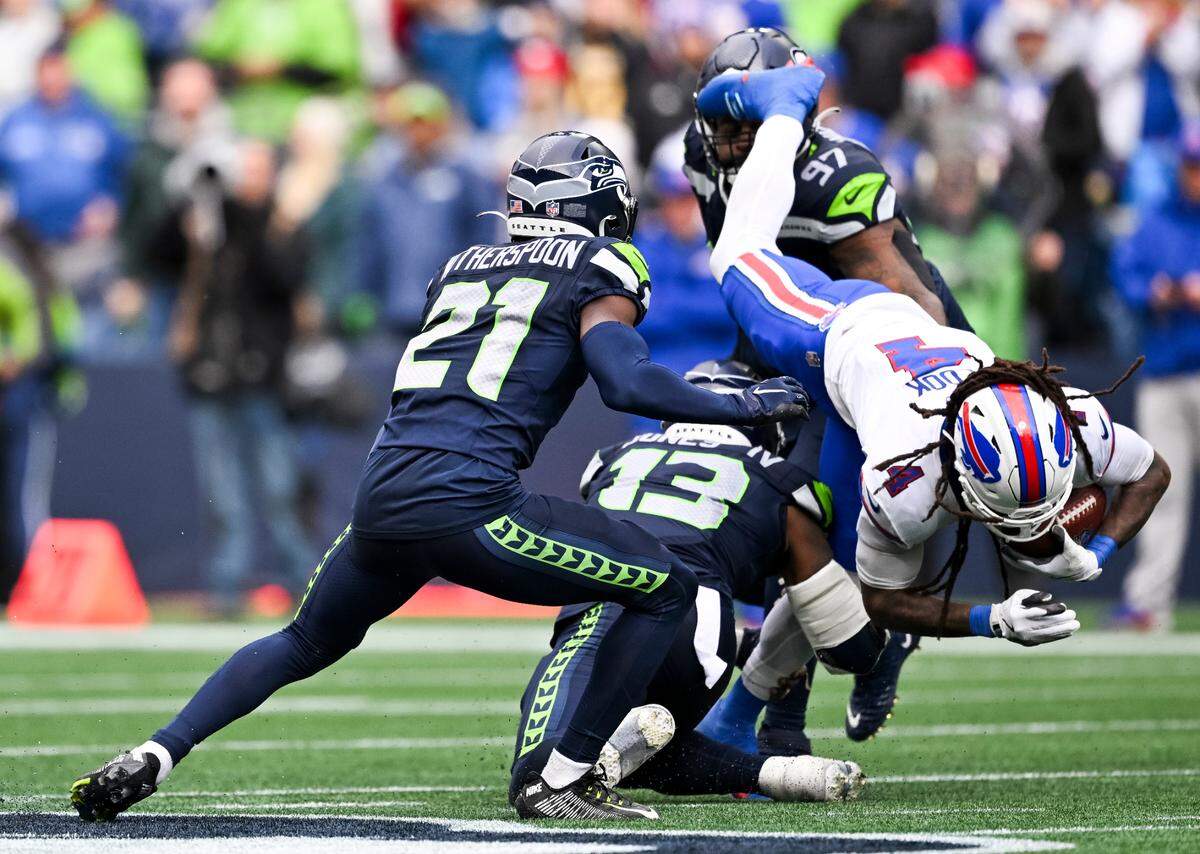 Buffalo Bills running back James Cook (4) flips over Seattle Seahawks linebacker Ernest Jones IV (13) and cornerback Devon Witherspoon (21) of the game at Lumen Field, on Sunday, Oct. 27, 2024 in Seattle, Wash.