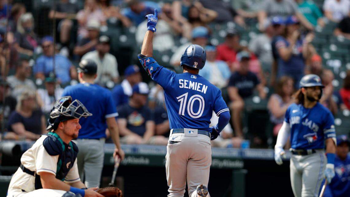 Toronto Blue Jays’ Marcus Semien points up after hitting a solo home run on a pitch from Seattle Mariners’ Yohan Ramirez during the ninth inning of a baseball game, Sunday, Aug. 15, 2021, in Seattle. The Blue Jays won 8-3. Mariners catcher Cal Raleigh is at left. (AP Photo/John Froschauer)