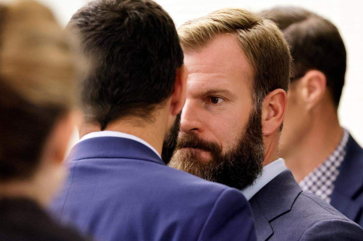 Officer Matthew Collins , right, talks with fellow officer Christopher “Shane” Burbank, left, during the trial of Tacoma Police officers accused in the death of Manny Ellis held at Pierce County Superior Court, Thursday, Nov. 2, 2023, in Tacoma, Wash. Officers Christopher Burbank, Matthew Collins and Timothy Rankine are charged. (John Froschauer / Pool Photo - AP)