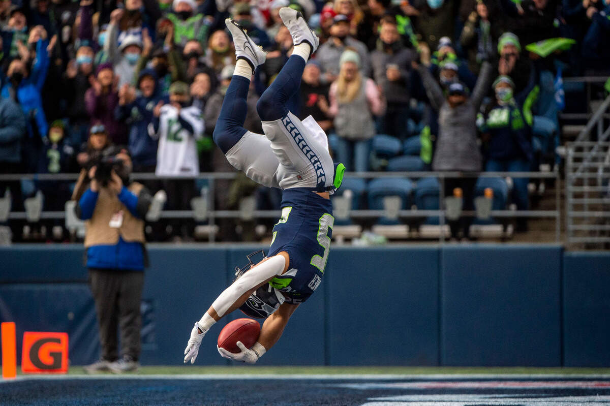 Seattle Seahawks running back Travis Homer (25) flips into the endzone after running a fake punt in for a touchdown in the first quarter of an NFL game against the San Francisco 49ers on Sunday at Lumen Field in Seattle.