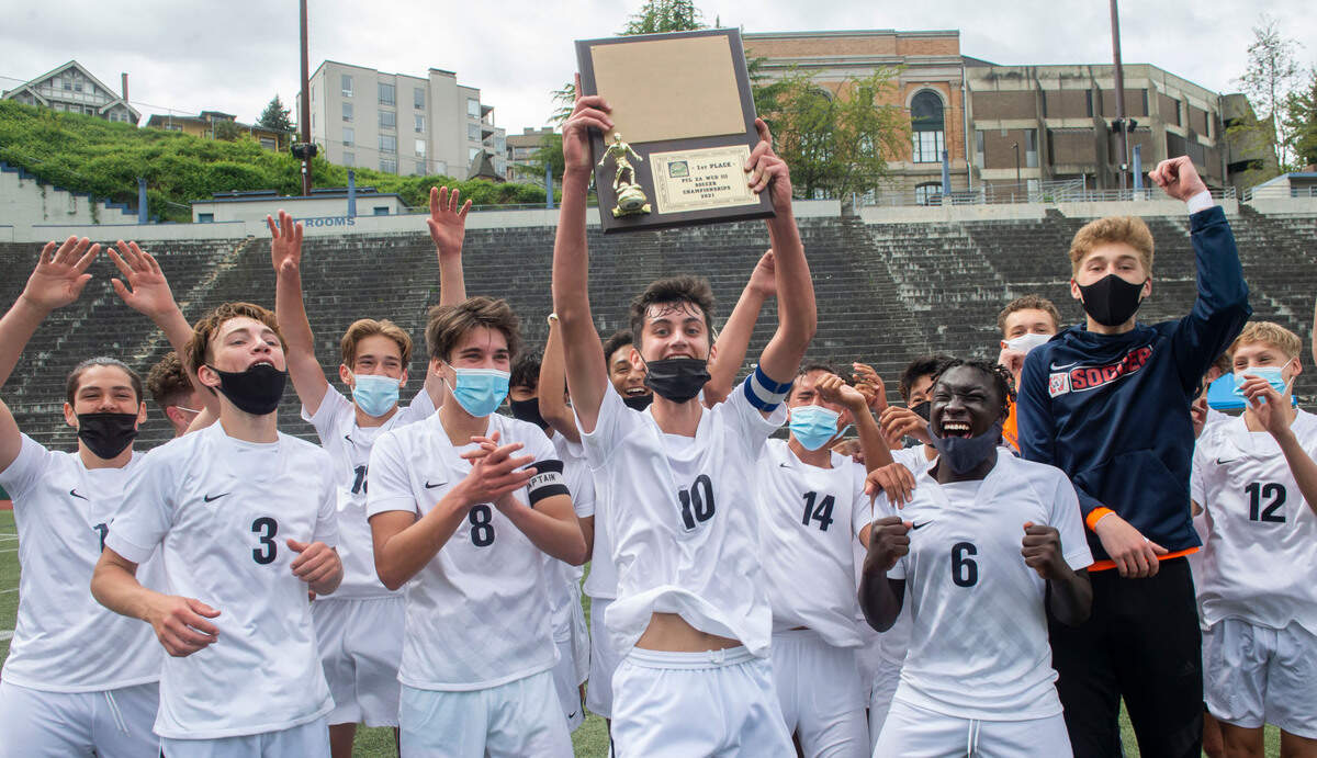 Wilson High’s Connor Tollan holds the 3A Pierce County League soccer championship trophy aloft as his teammates cheer following the Rams’ 2-0 victory over Stadium Saturday, May 1, at Stadium High School.