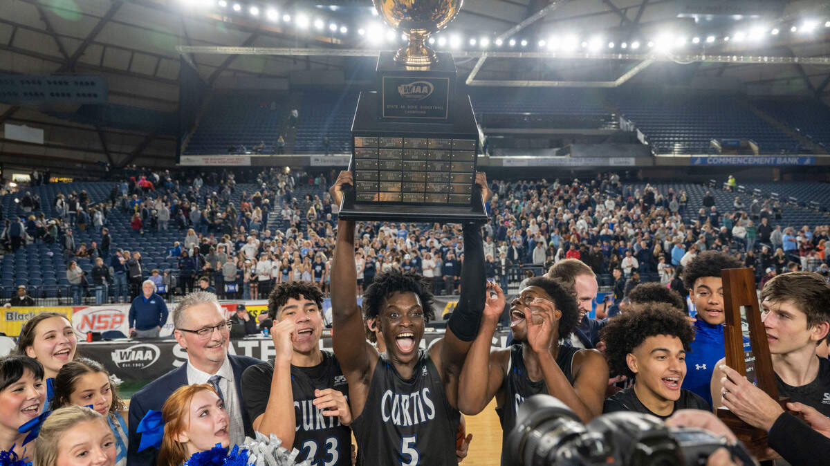 Zoom Diallo (5) hoists the state championship trophy as Curtis players celebrate beating Olympia, 49-43, to win the Class 4A title for the second consecutive year on Saturday, March 4, 2023, in Tacoma, Wash.