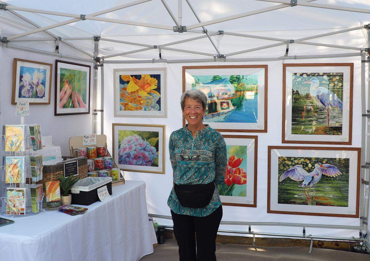 Watercolor artist Beth Owen stands among pieces of her work at the 2023 Summer Art Festival in downtown Gig Harbor. Owen is a returning artist at the 2024 festival.