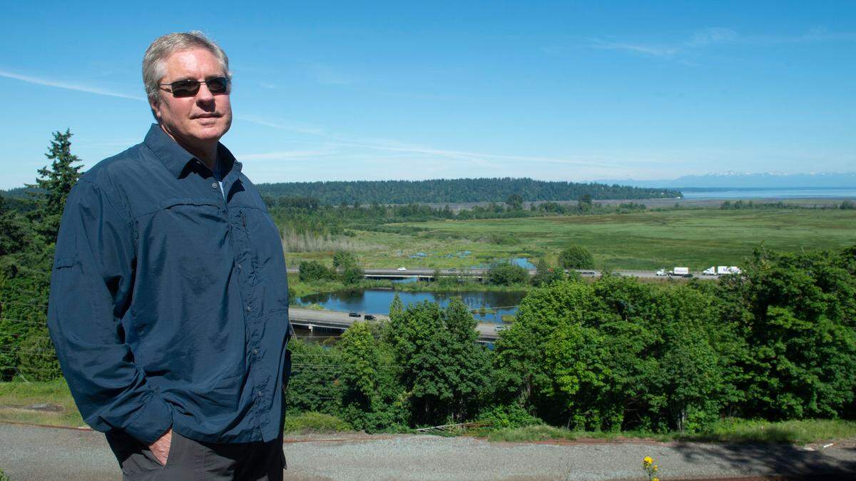 Bill Adamson, a manager at the military lobbying group South Sound Military and Communities Partnership, stands at a viewpoint where Interstate 5 crosses the Nisqually River delta. Adamson is worried about the potential impacts flooding could have on the economy and Joint Base Lewis-McChord, nine miles north of the bridge. “I-5 is the lifeline of commerce for this South Sound region,” Adamson said.