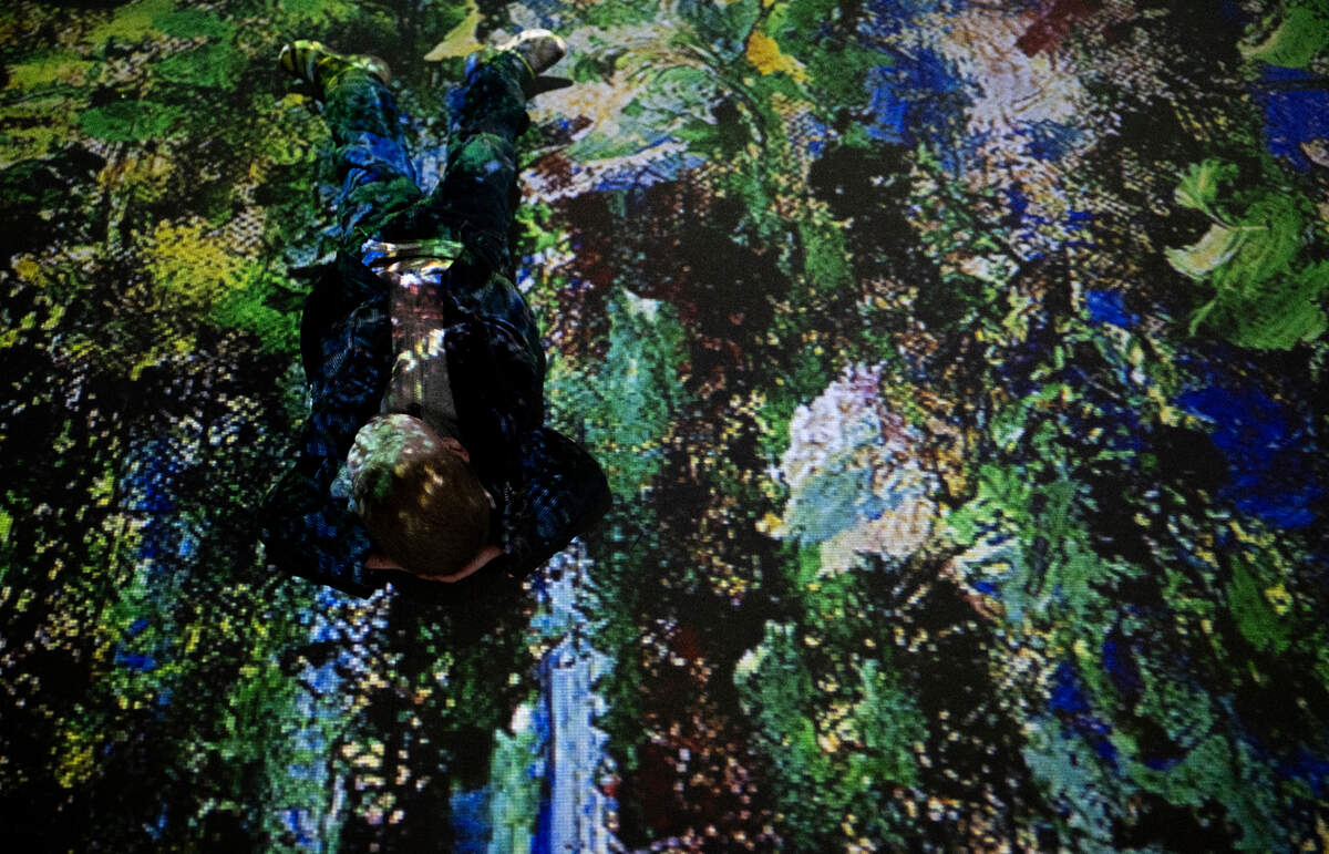 Peregrine Feuk, 3, lays on the floor as Monet’s painting as projected on the floor and walls of the Imagine Monet experience at the Tacoma Armory, on Thursday, April 4, 2024, in Tacoma, Wash.