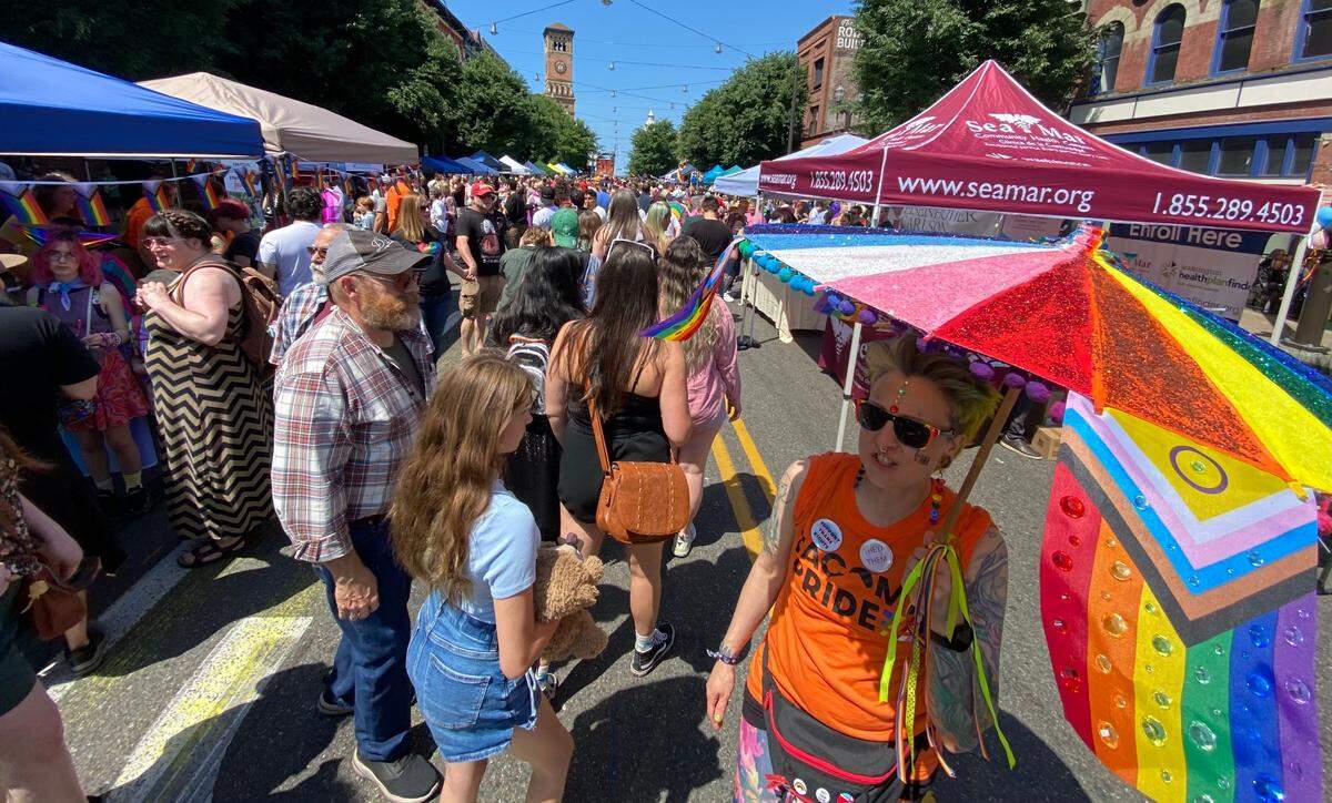 A volunteer with Tacoma Pride welcomes attendees at South 9th Street and Pacific Avenue Saturday, July 8, 2023.
