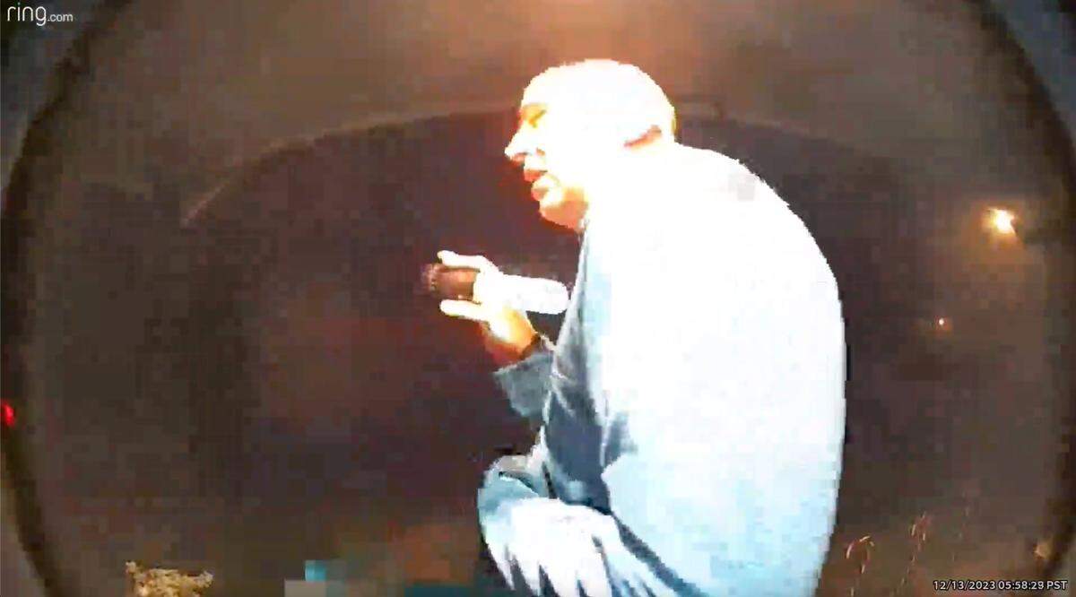In this frame from a Ring doorbell cam, Kevin Larson shelters from a barred owl on Angelica and Richard Sanchez’s porch, on Dec. 13, 2023, in Tacoma, Wash.