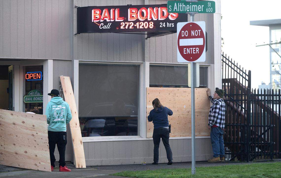 Workers board up the windows at CJ Johnson Bail Bonds across the street from the County-City Building in Tacoma, Washington, on Thursday, Dec. 21, 2023, following the not-guilty verdicts for three Tacoma police officers criminally charged in the death of Manny Ellis.
