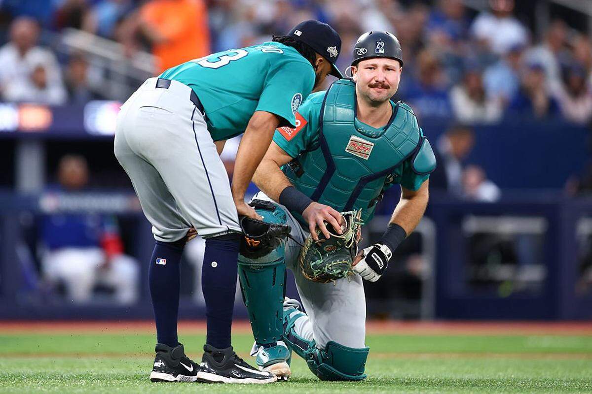 TORONTO, ONTARIO - OCTOBER 13: Eduard Bazardo #83 of the Seattle Mariners checks on teammate Cal Raleigh #29 after a play against the Toronto Blue Jays during the fourth inning in game two of the American League Championship Series at Rogers Centre on October 13, 2025 in Toronto, Ontario. (Photo by Vaughn Ridley/Getty Images)