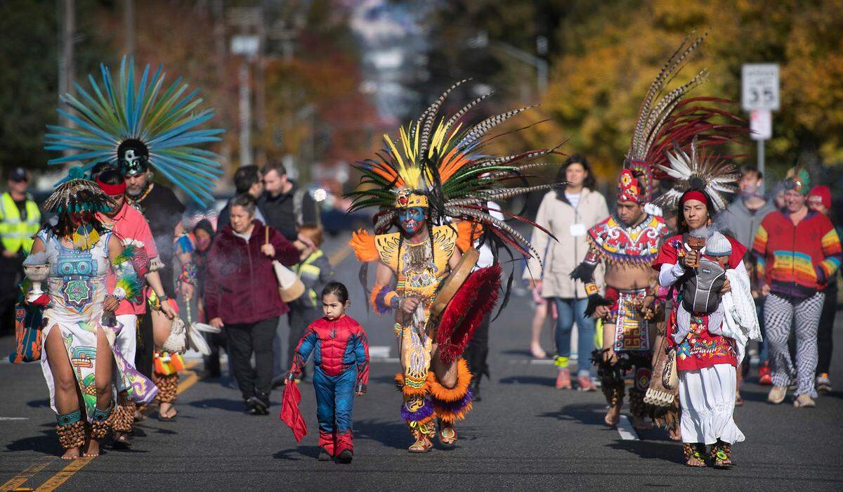 Victor Maldonado (center) leads dancers as they march south on Portland Avenue to the Dia de los Muertos celebration at the Eastside Community Center in Tacoma, Washington, on Saturday, Oct. 29, 2022.