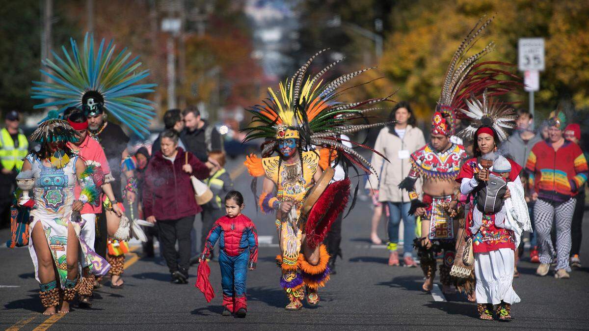 Victor Maldonado (center) leads dancers as they march south on Portland Avenue to the Dia de los Muertos celebration at the Eastside Community Center in Tacoma, Washington, on Saturday, Oct. 29, 2022.