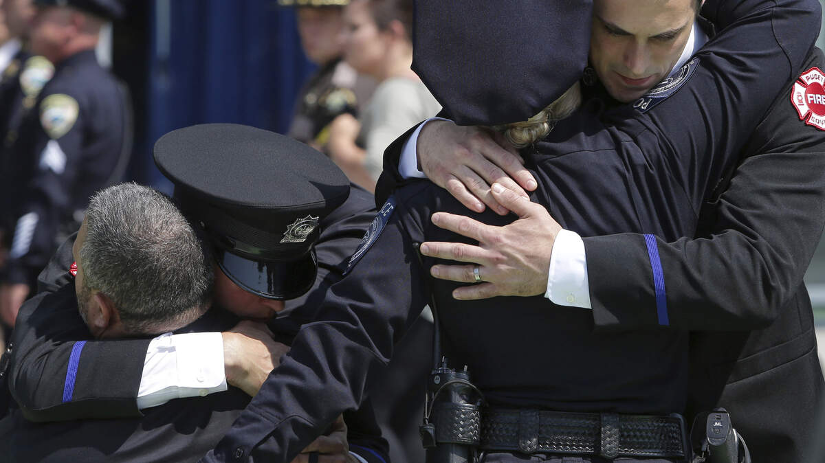 Attendees hug outside Tuesday’s memorial service for Kent Police Officer Diego Moreno, who was killed in the line of duty during a high speed chase.