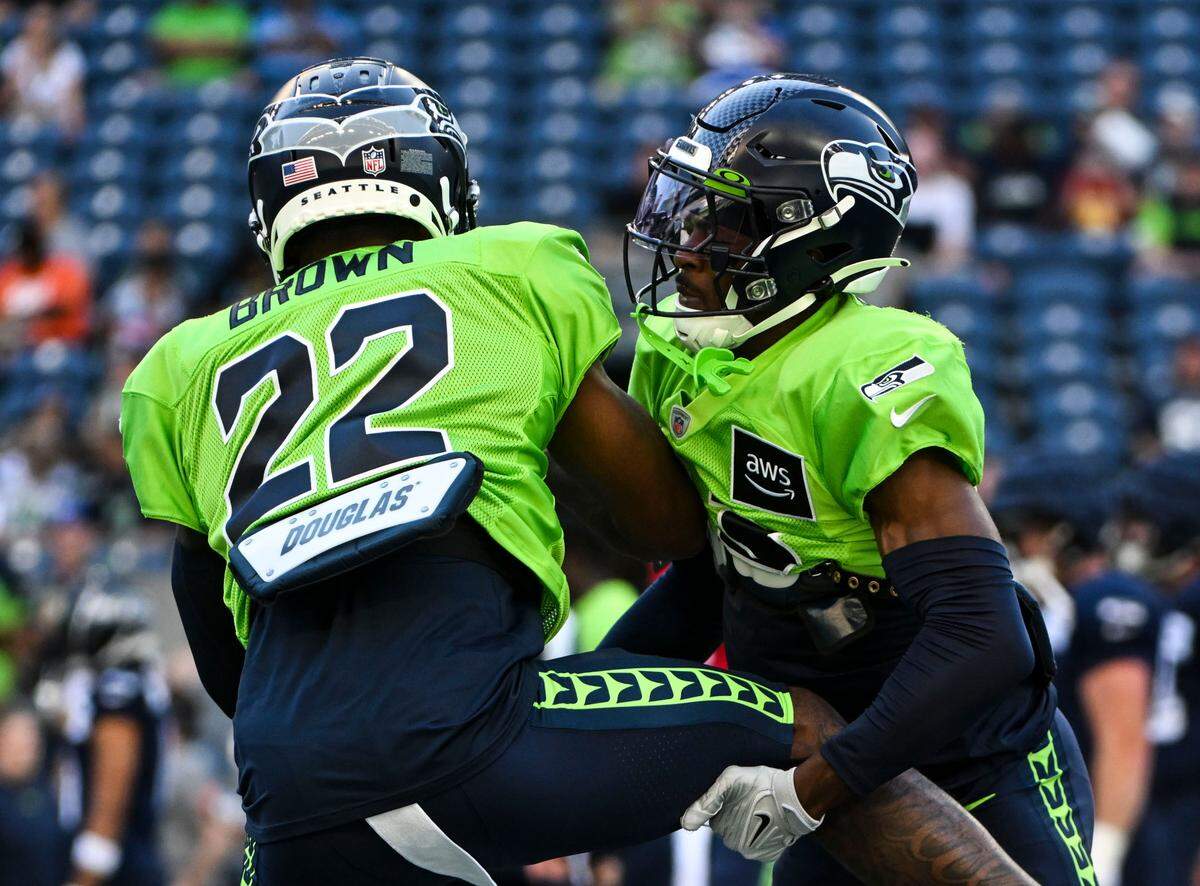 Seattle Seahawks cornerback Tre Brown (22) and cornerback Artie Burns (23) run drills during warm-ups before the mock game at Lumen Field, Friday, Aug. 4, 2023, in Seattle, Wash.