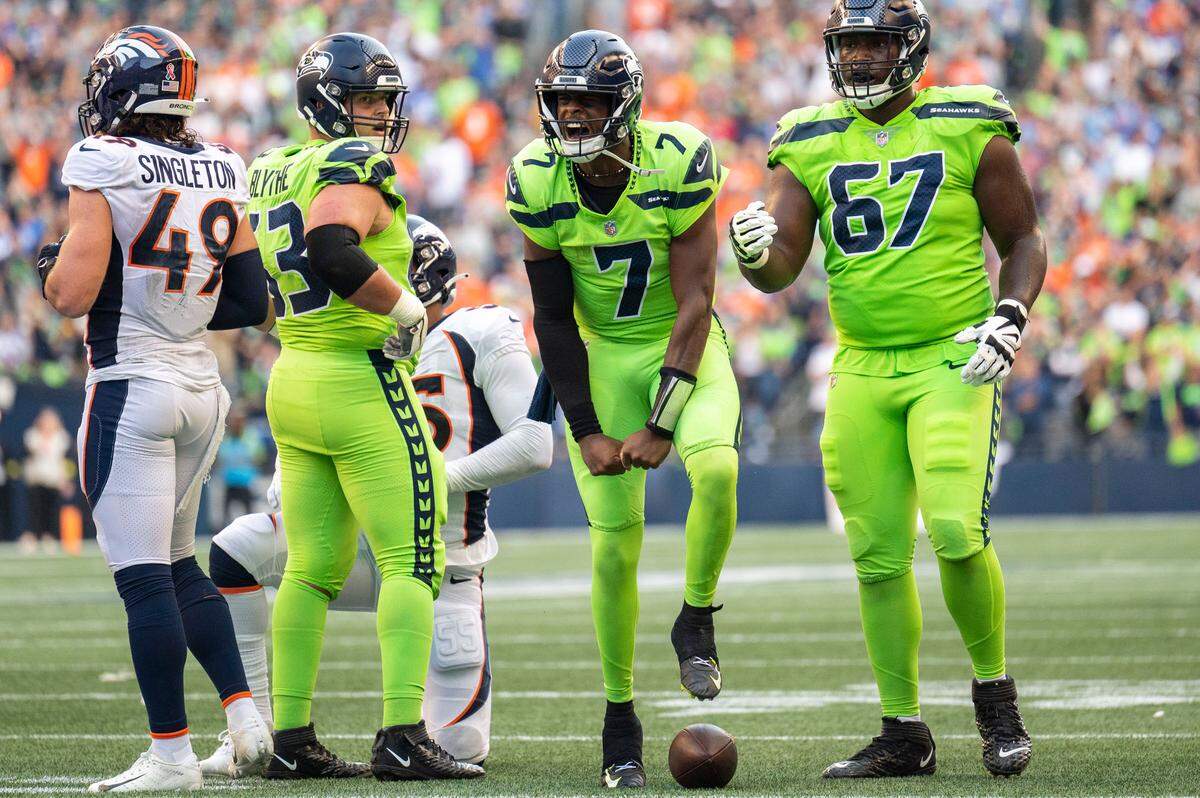 Seattle Seahawks quarterback Geno Smith (7) celebrates after scrambling for a gain as Denver Broncos linebacker Alex Singleton (49) walks away in the second quarter of an NFL game on Monday, Sept. 12, 2022, at Lumen Field in Seattle. Seattle Seahawks offensive tackle Abraham Lucas (72) was called for holding on the play, negating the run gain.