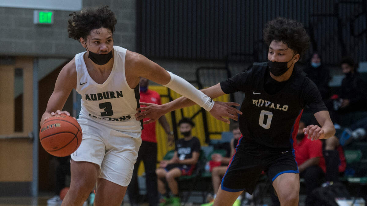 Auburn High School guard Maleek Arington brings the ball up the court as Kent Meridian guard Dane Lewis defends in a Class 3A North Puget Sound League boys basketball game on Tuesday, June 15, 2021 in Auburn, Wash.