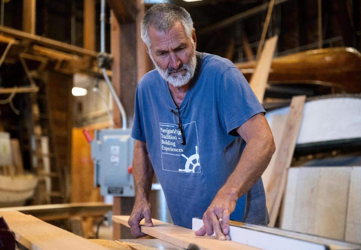 Anthony “Mike” Vlahovich cuts a board for a Croatian fishing boat that is being built as part of “The Batana Project” at the Gig Harbor Boat Shop in Gig Harbor, Wash. on Wednesday, July 20, 2022. Once the boat is complete, the boat shop will host an event to reveal it Sept. 3.