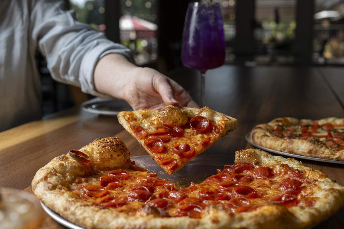 A slice of Holy Pepperoni pizza is lifted from the table at The Edit Social House on Thursday, May 21, 2026, at the Oakbrook Golf Club in Lakewood, Wash.