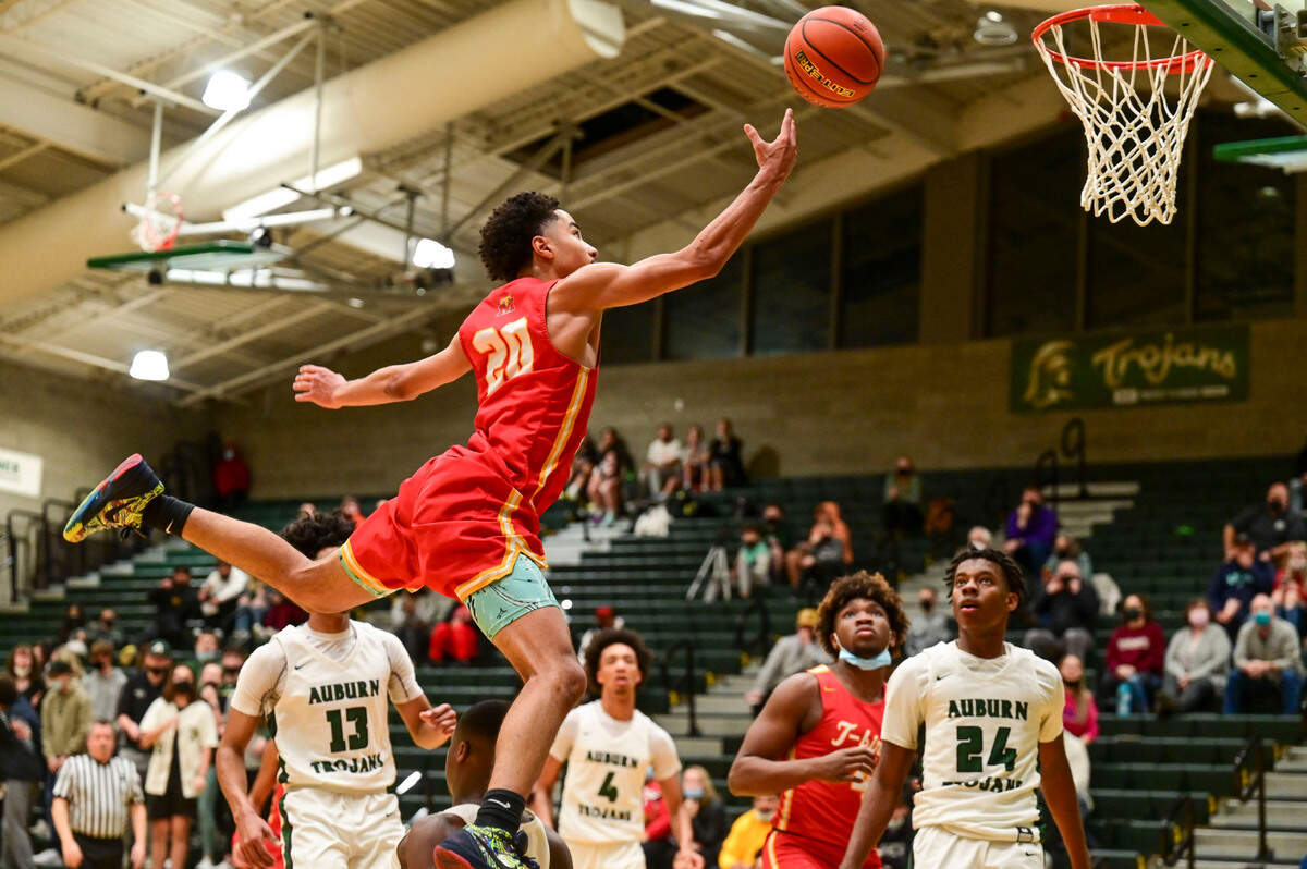 Mount Tahoma guard Asjon Anderson (20) jumps over Auburn guard Ryan Mpouli (5) as he attempts a layup during the third quarter of a non-league game on Thursday, Jan. 20, 2022, at Auburn High School.