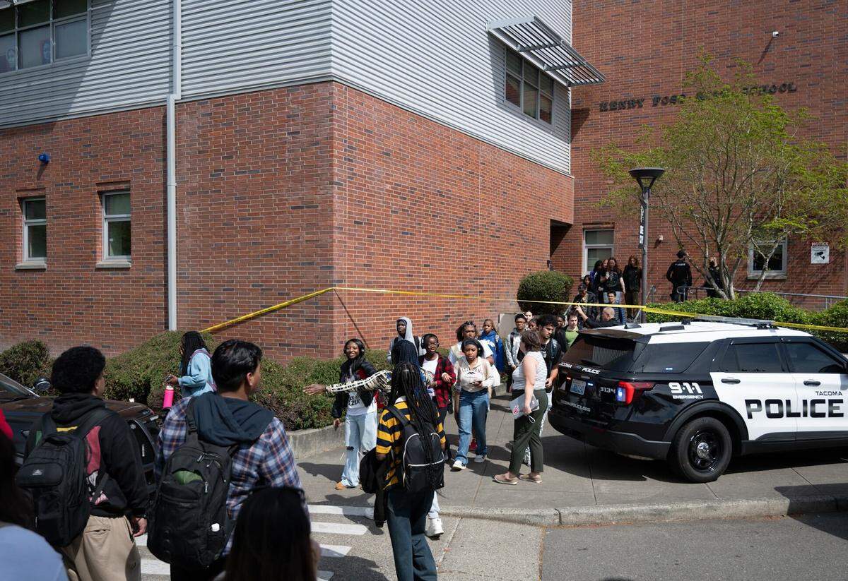 Foss High School students cross underneath police tape as they leave the school after a stabbing incident injured six people on Thursday, April 30, 2026, in Tacoma, Wash.