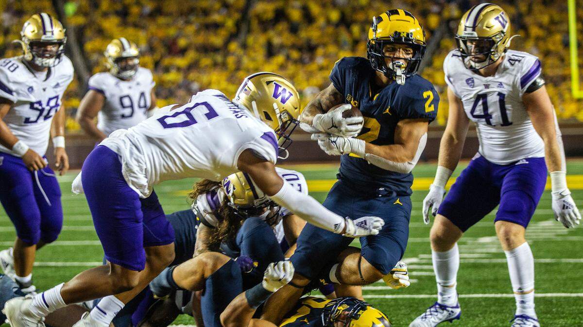 Michigan running back Blake Corum (2) steps over tight end Erick All (83) and past Washington defensive back Cameron Williams (6) to score a touchdown in the fourth quarter of an NCAA college football game in Ann Arbor, Mich., Saturday, Sept. 11, 2021. (AP Photo/Tony Ding)