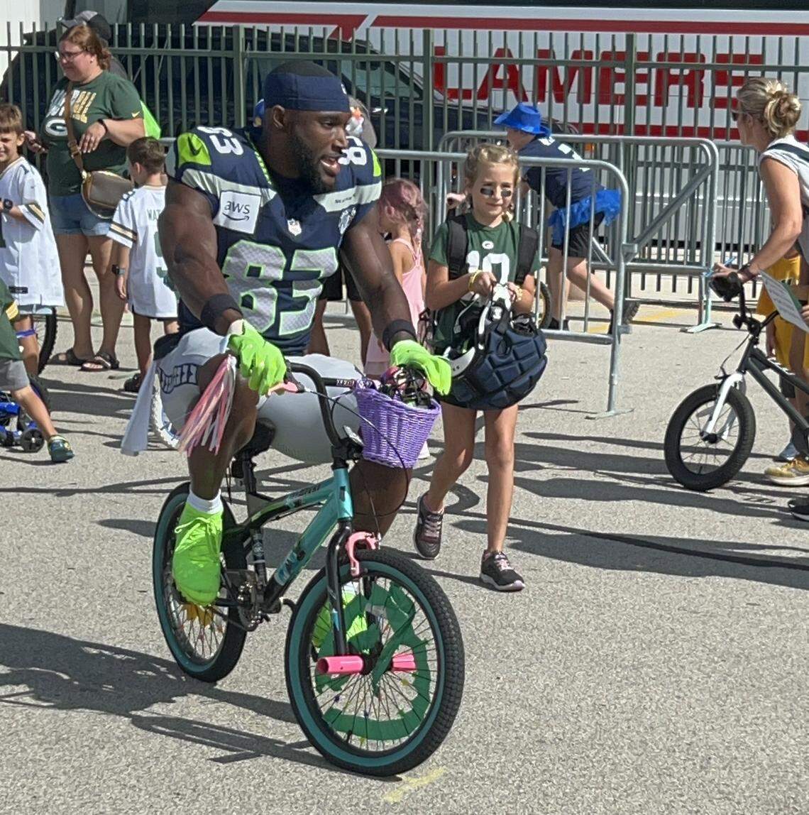 Wide receiver Dareke Young chooses a local girl’s small, not-football-adorned bike to ride from the Seahawks’ locker room at Lambeau Field to the field for Seattle’s NFL preseason joint practice with the Packers in Green Bay, Wisconsin, Thursday, Aug. 21, 2025.