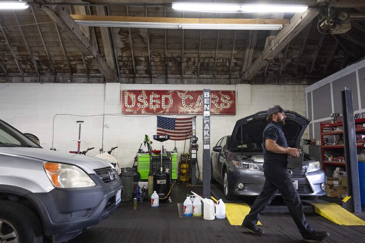 Ball Auto owner Drew Barnett carries a car battery across the auto shop on Monday, June 29, 2026, in Tacoma, Wash.