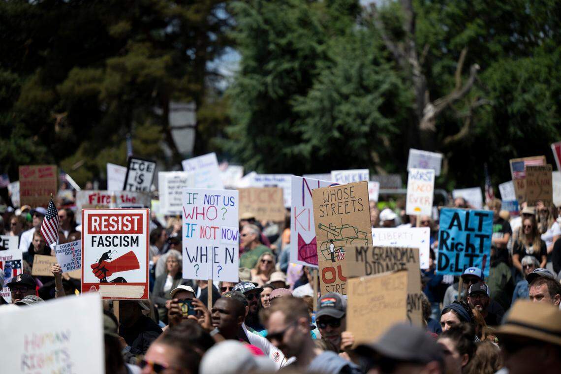 People hold a variety of signs decrying fascism, Trump during a “No Kings” protest at People’s Park on Saturday, June 14, 2025, in Tacoma, Wash.