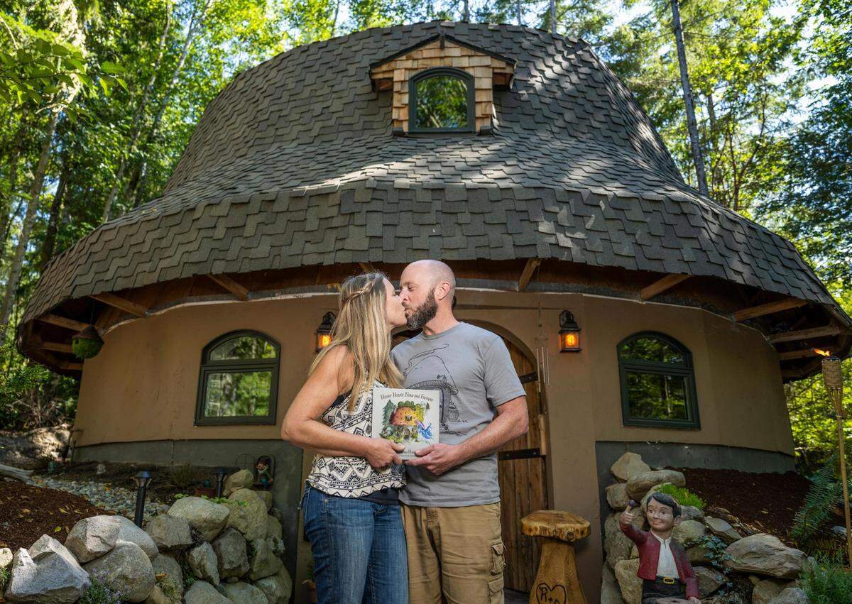 Rod Collen and his fiancé, Shannon Garrett, kiss for a portrait in front of their mushroom house that they built from the ground up together on their property in Lakebay, Wash. August 13, 2022.